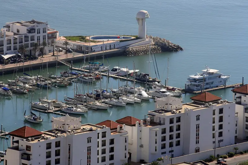 Yachts moored in Agadir Marina beside white buildings and the harbour wall