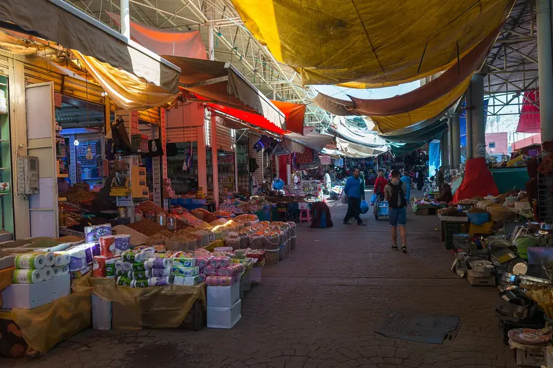 Colourful stalls and shoppers in a covered lane of Souk El Had, Agadir